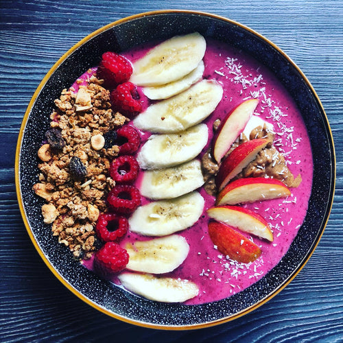 Vegan granola with bananas, raspberries, apple slices and yogurt.